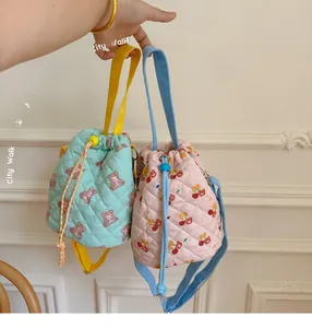 Close-up of quilted cotton drawstring bucket bags with cute bear and cherry patterns