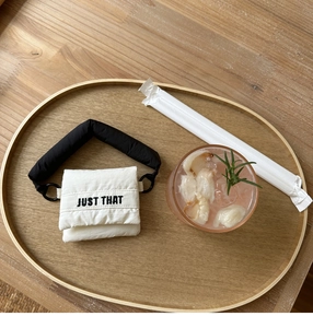 Macro shot of mini puffer storage bag with Just That embroidery on wooden tray