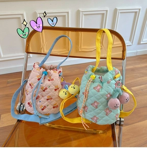 Detail of quilted bucket bags featuring cute cherry and bear prints with plush charms
