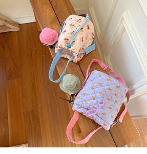 Close-up of quilted macaron color bucket bags with cartoon bear charms on wooden bench