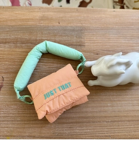 Macro shot of fluffy orange mini storage bag with mint handles on a wooden table