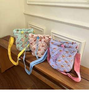 Detailed view of quilted cotton bucket bags with colorful bear and cherry embroidery