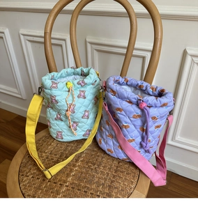 Close-up of quilted macaron color bucket bags with bear prints on a wooden chair