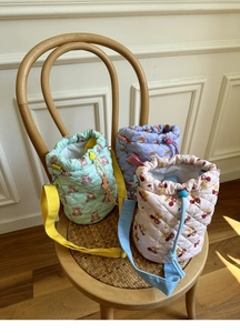 Quilted drawstring bucket bags in macaron colors with cute bear prints on a wooden chair