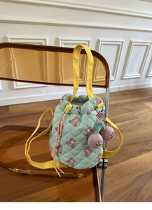 Close-up of mint green quilted bucket bag with bear print and cute cherry charm detail