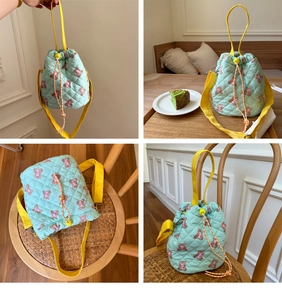 Detailed view of mint green quilted bucket bag with cartoon bear patterns and yellow straps