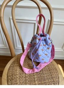 Detail of purple quilted bucket bag featuring cute bear patterns and pink drawstring straps