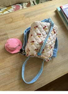 Close-up of quilted bucket bag with cherry bear patterns and pink hat charm detail