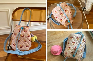 Close-up of pink quilted bucket bag with embroidered bears, cherries and blue handles