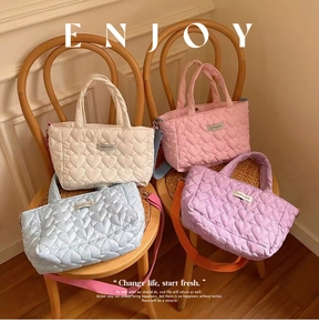Detail of heart quilted bags in white pink blue and purple colors with crossbody straps