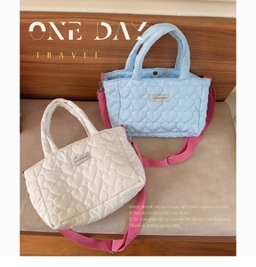 Detail of soft heart-quilted tote bag featuring pink crossbody strap and fashion label