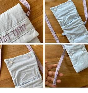 Detail of light blue quilted phone bag with purple embroidery and resin snap buttons