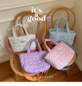 Quilted heart pattern handbags in four colors displayed on chairs for a cozy aesthetic