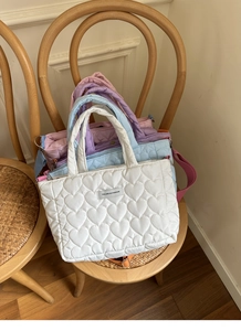 Close-up of quilted heart patterns and fashion labels on colorful puffy handbags
