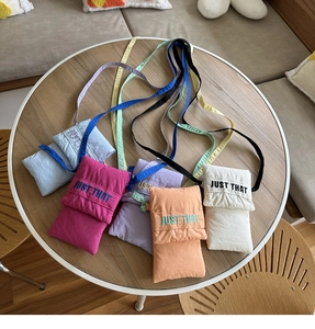 Detail showing various colors of nylon ruched crossbody phone bags with JUST THAT embroidery