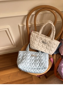 Detailed heart quilting texture on a soft ivory tote bag with colorful nylon strap