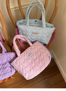 Detail of heart quilted nylon handbags in light blue pink and purple with fabric straps