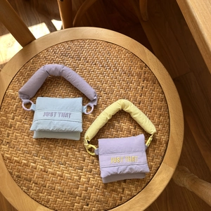 Mini puffy fabric handbag with JUST THAT embroidery on a woven wooden chair
