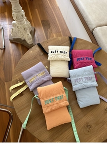 Detail of five mini canvas crossbody phone bags with JUST THAT embroidery and shoulder straps