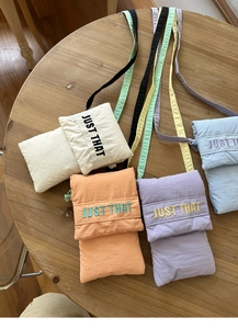 Macro shot of nylon phone bags in cream, orange, purple, and blue colors on a wooden table
