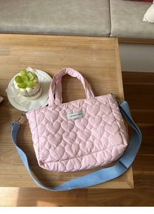 Detailed view of pink quilted heart bag with blue straps and stylish fashion label