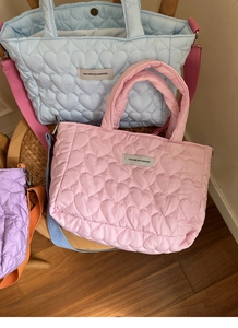Close-up of heart-quilted texture on soft handbags in pastel blue, pink, and purple colors