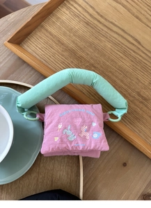 Close-up of pink quilted fabric pouch with cartoon animal prints and mint green handle