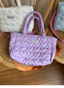 Close-up of heart quilted nylon bags in white, purple and blue on a vintage chair