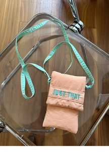 Detail of quilted mini phone bag in coral pink bubble fabric with mint green strap