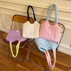 Detail of heart-quilted texture and contrast straps on canvas tote bags in four colors