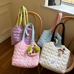 Close-up of quilted heart patterns on colorful canvas bags with cute plush charms