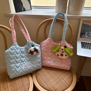 Detail of heart quilted canvas tote bags in contrasting pink and blue on a wooden chair