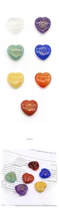Detailed view of seven heart-shaped chakra healing crystals with golden symbols on a magazine