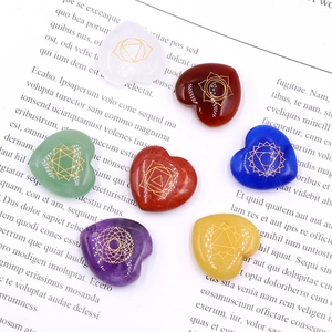 Set of 7 polished heart-shaped chakra stones with gold symbols on a vintage book