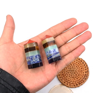 Hand holding two natural seven chakra crystal hexagonal pillars for healing meditation
