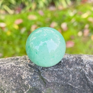 Green aventurine crystal sphere 25mm polished natural stone ball on gray rock surface