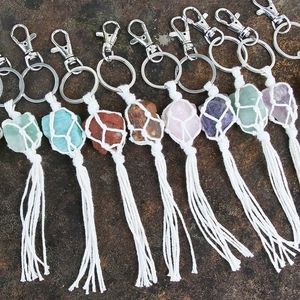 Handwoven macrame crystal keychains with natural gemstones and tassels on a stone surface
