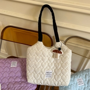 Detail showing heart-shaped quilting texture and contrast handles on tote bags