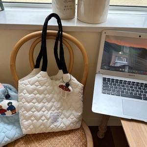 Close-up of heart-shaped quilted texture and cute mushroom charm on cream canvas bag