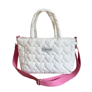 White heart quilted soft tote bag with a pink adjustable shoulder strap and woven labels