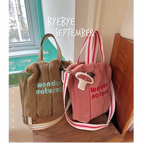 Detail of lamb wool tote bags featuring wonder embroidery and striped webbing handles