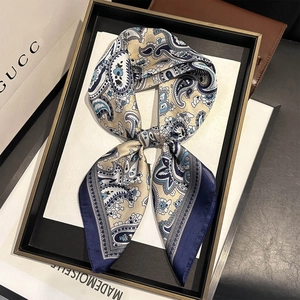 Élégant foulard en soie à motif paisley bleu marine et beige, présenté dans un cadre de luxe