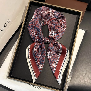 Carré de soie luxueux avec motifs paisley marine et bordeaux sur un plateau cadeau