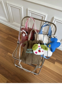 Detail of plush tote bags with wonder nature embroidery and cute cartoon pendants