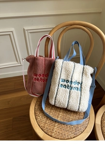 Detail of pink and white faux fur tote bags with wonder natural embroidery on a chair