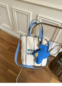 Detail of wonder nation embroidery on beige faux shearling tote with blue straps