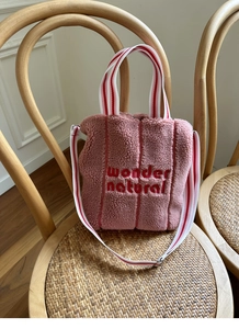 Detail of pink faux shearling tote bag with red wonder natural embroidery and striped handles
