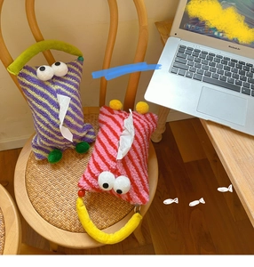 Close-up of cute striped plush car tissue holders with cartoon eyes and handles