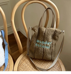 Detail of wonder natural embroidery on brown sherpa fleece tote bag with striped strap