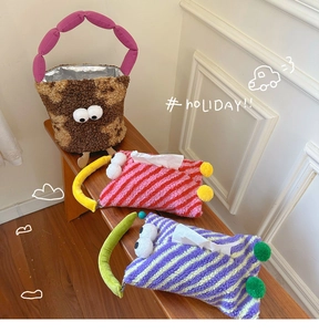 Detail of plush monster tissue covers and insulated bag on a wooden bench